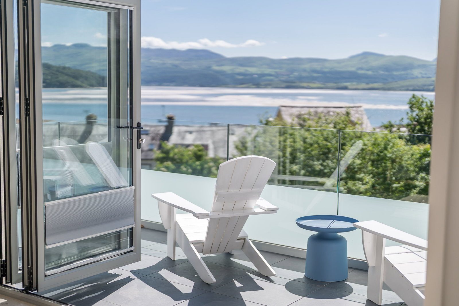 Open bi-fold doors onto the terrace, with sea and mountain views over Borth-y-Gest bay